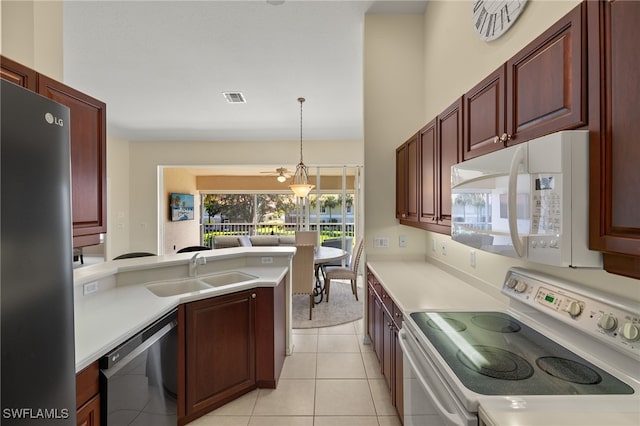 kitchen with visible vents, a sink, light countertops, white appliances, and reddish brown cabinets