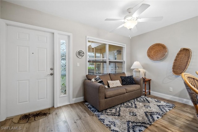 living room with wood finished floors, a ceiling fan, and baseboards