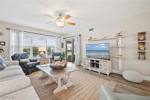 living area with baseboards, visible vents, ceiling fan, and wood finished floors