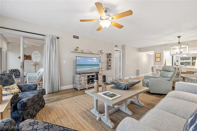 living room featuring visible vents, wood finished floors, and ceiling fan with notable chandelier