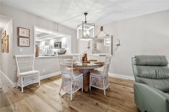 dining space featuring a notable chandelier, light wood-type flooring, and baseboards