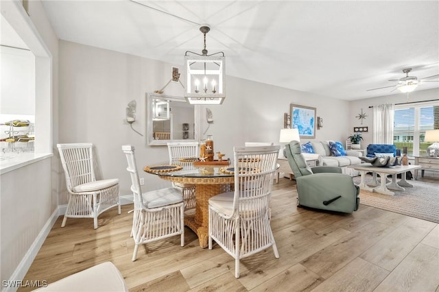 dining room featuring ceiling fan with notable chandelier, light wood-style flooring, and baseboards