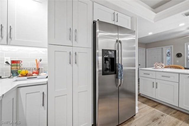 kitchen with light wood finished floors, white cabinets, backsplash, and stainless steel fridge with ice dispenser