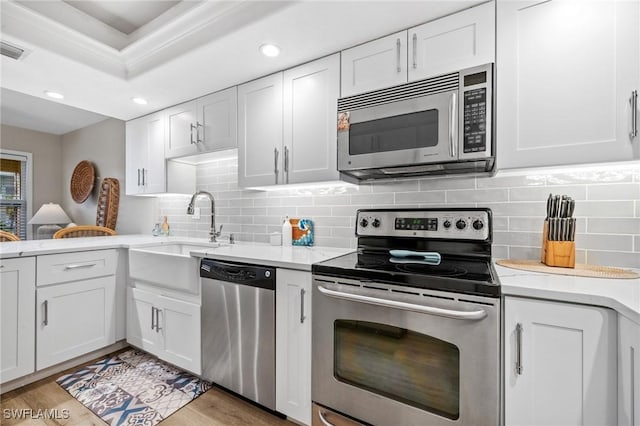 kitchen featuring stainless steel appliances, light countertops, white cabinets, and a sink