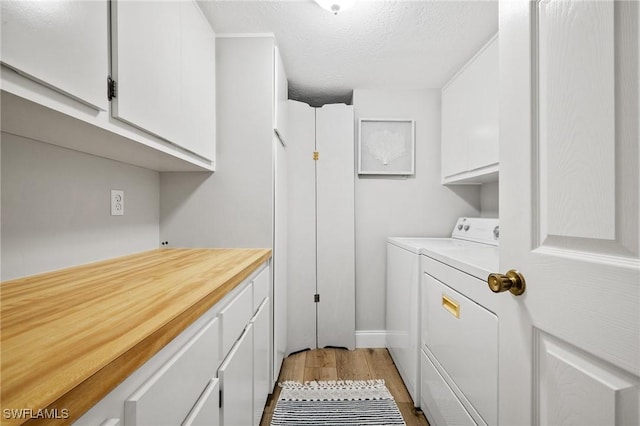 laundry room featuring cabinet space, washer and clothes dryer, a textured ceiling, and wood finished floors