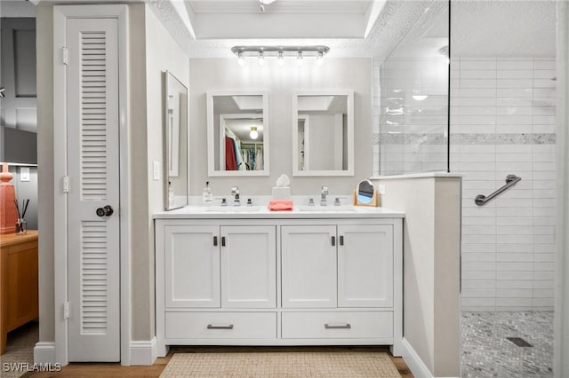 full bathroom featuring a walk in shower, double vanity, a sink, and baseboards