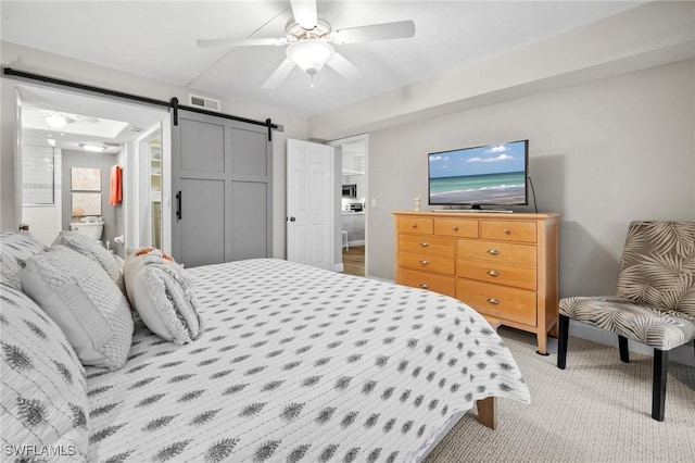 carpeted bedroom featuring a ceiling fan, visible vents, and a barn door