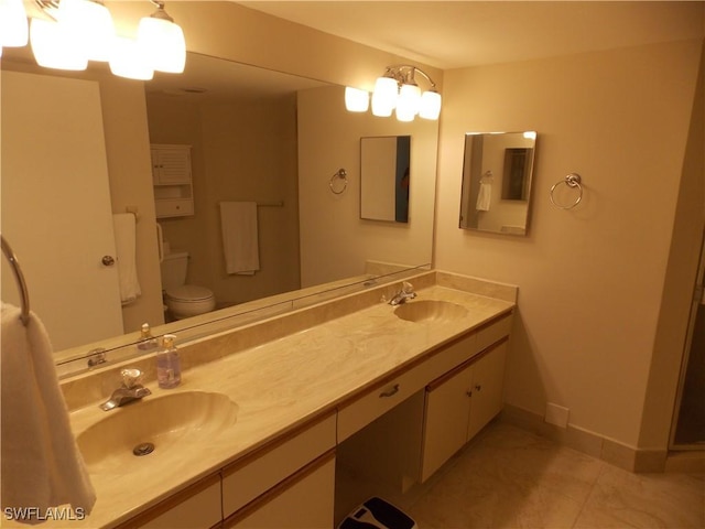 full bathroom featuring double vanity, a sink, toilet, and baseboards