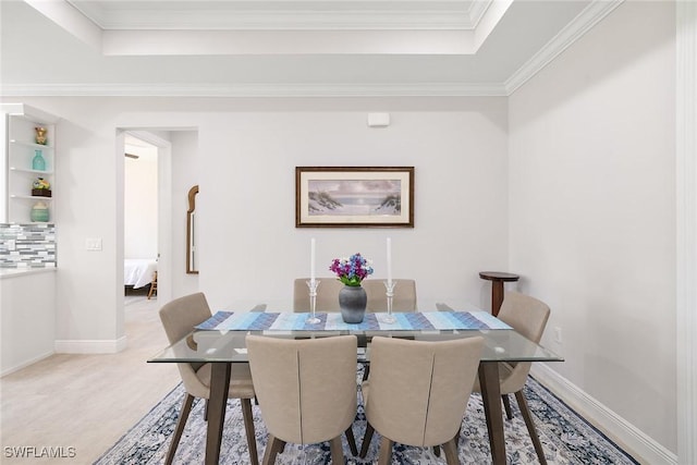 dining area featuring ornamental molding, a tray ceiling, and baseboards