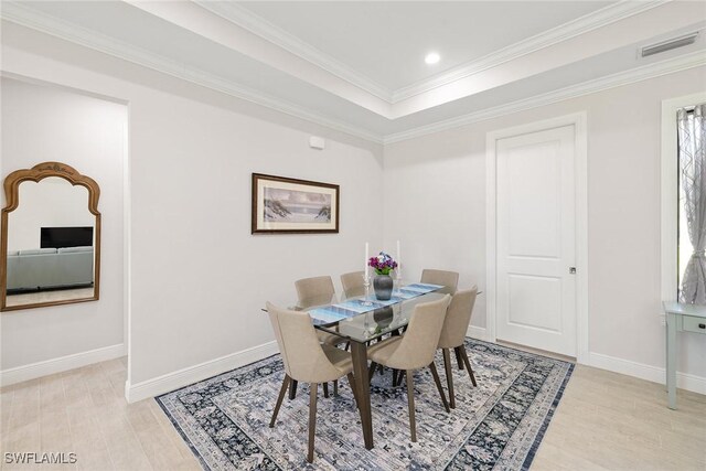 dining room with baseboards, light wood-type flooring, visible vents, and crown molding