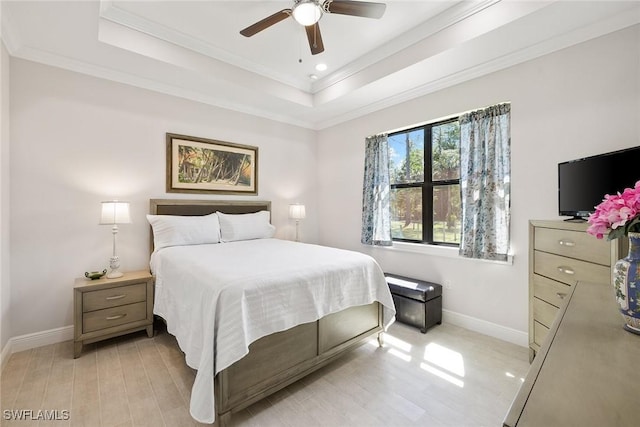 bedroom with baseboards, a tray ceiling, light wood finished floors, and crown molding