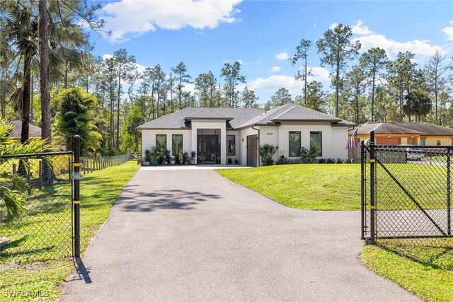 view of front of home with aphalt driveway, a gate, fence, a front yard, and stucco siding