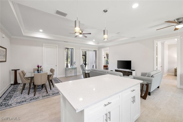 kitchen with crown molding, a raised ceiling, visible vents, hanging light fixtures, and white cabinetry