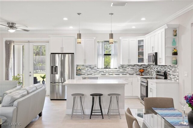 kitchen featuring visible vents, appliances with stainless steel finishes, open floor plan, a kitchen bar, and a sink