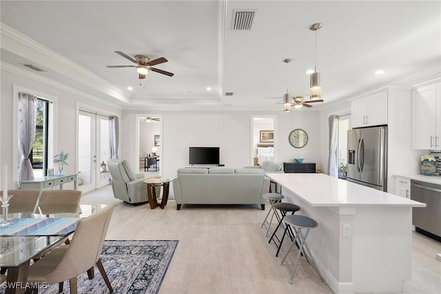 kitchen with stainless steel appliances, a kitchen island, white cabinets, light countertops, and ornamental molding