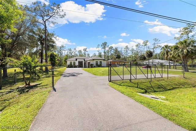 view of front of property featuring a gate, fence, aphalt driveway, and a front yard