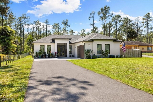 view of front facade with driveway, stucco siding, a garage, and a front yard