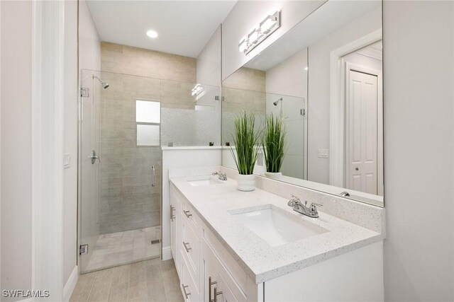 bathroom featuring a sink, a shower stall, and double vanity