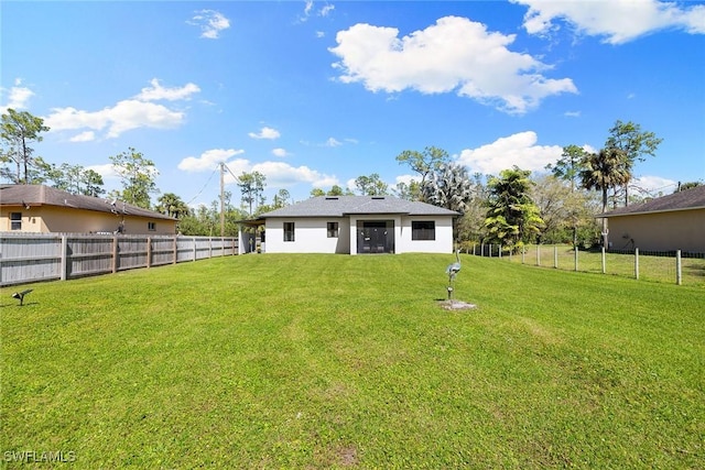 rear view of house featuring a fenced backyard, a yard, and stucco siding