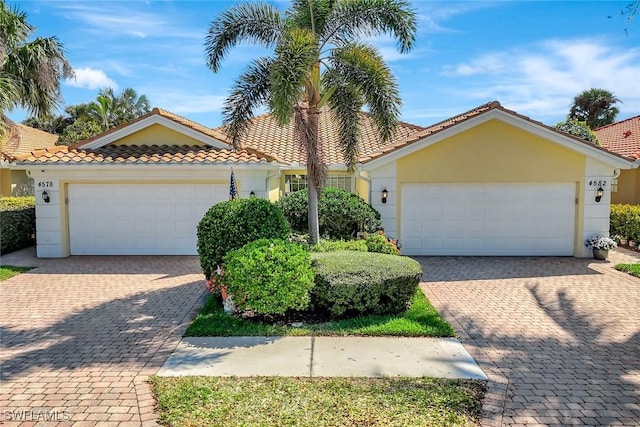 view of front of home with an attached garage, a tiled roof, and stucco siding