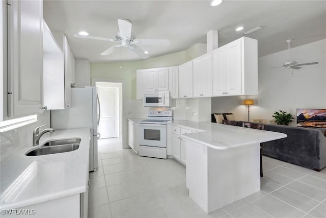 kitchen with backsplash, white cabinets, a sink, white appliances, and a peninsula