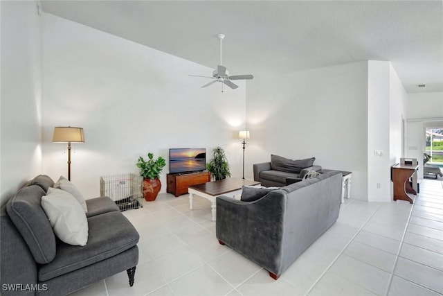 living area with light tile patterned floors, ceiling fan, and a high ceiling