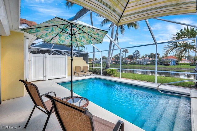 pool with a patio area, glass enclosure, and a water view