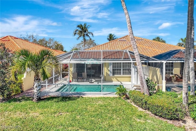 back of property featuring an outdoor pool, a patio, a tile roof, a lanai, and a yard