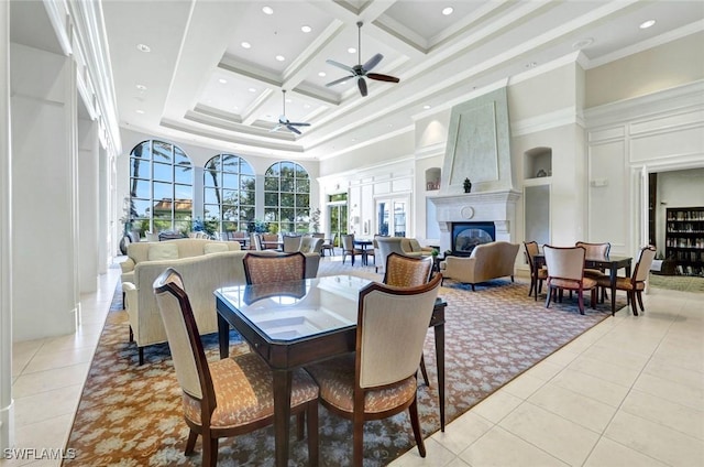 dining room with a glass covered fireplace, coffered ceiling, a towering ceiling, and light tile patterned flooring