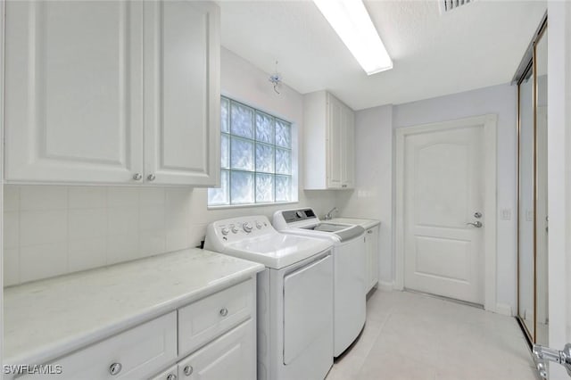 laundry area featuring light tile patterned floors, washing machine and dryer, and cabinet space