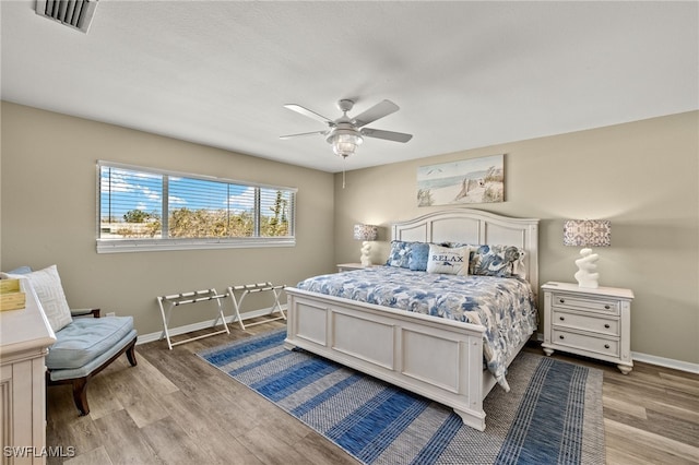 bedroom featuring visible vents, ceiling fan, baseboards, and wood finished floors