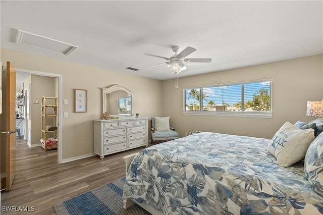 bedroom featuring attic access, baseboards, visible vents, ceiling fan, and wood finished floors