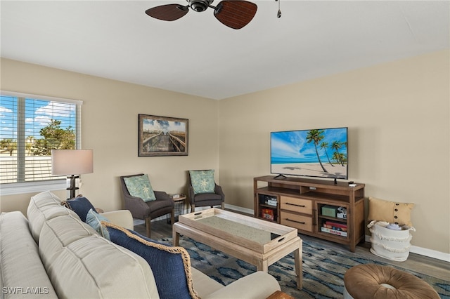 living room with ceiling fan, baseboards, and wood finished floors