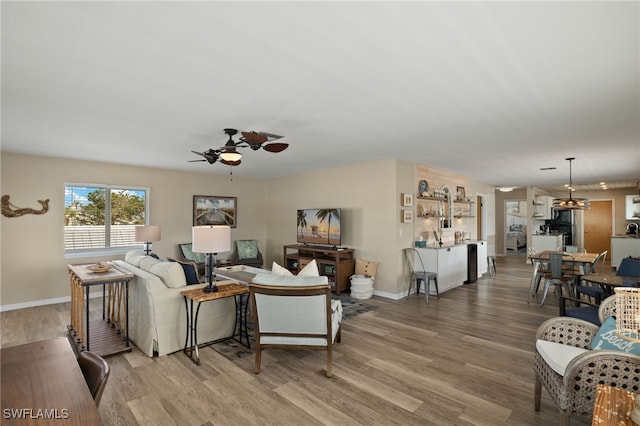 living area featuring light wood-type flooring, ceiling fan, and baseboards