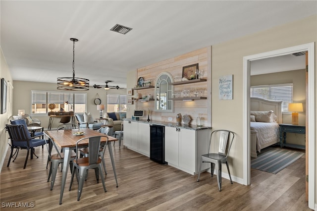 dining space with beverage cooler, visible vents, indoor wet bar, and wood finished floors