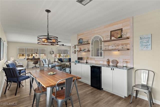 dining room with light wood finished floors, beverage cooler, visible vents, and baseboards