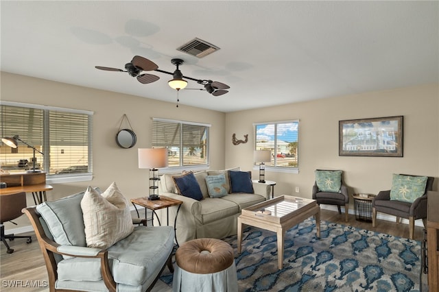 living room featuring baseboards, visible vents, ceiling fan, and wood finished floors