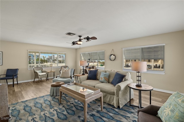 living room featuring visible vents, ceiling fan, baseboards, and wood finished floors