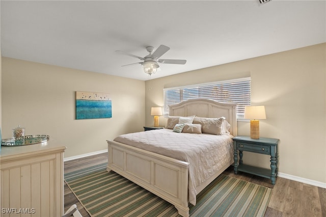 bedroom with a ceiling fan, baseboards, and dark wood-type flooring