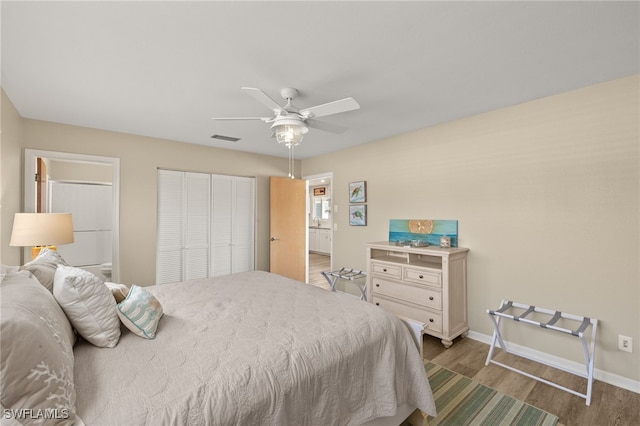 bedroom with ceiling fan, wood finished floors, visible vents, baseboards, and a closet