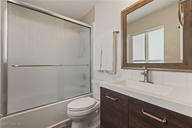 full bath featuring combined bath / shower with glass door, vanity, and toilet