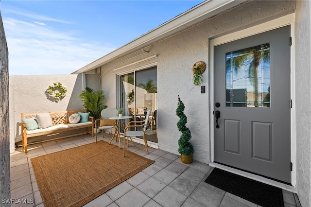 view of exterior entry with a patio area, an outdoor hangout area, and stucco siding