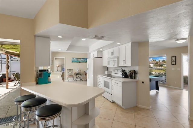 kitchen with white appliances, light countertops, a kitchen breakfast bar, and light tile patterned floors