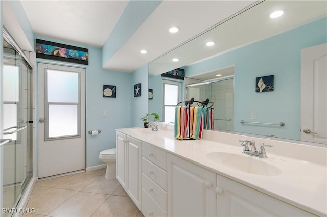 bathroom featuring double vanity, a stall shower, a sink, and tile patterned floors