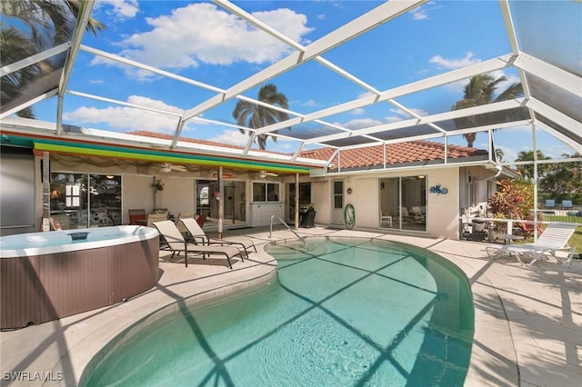 rear view of house with a hot tub, a tiled roof, a lanai, a patio area, and stucco siding