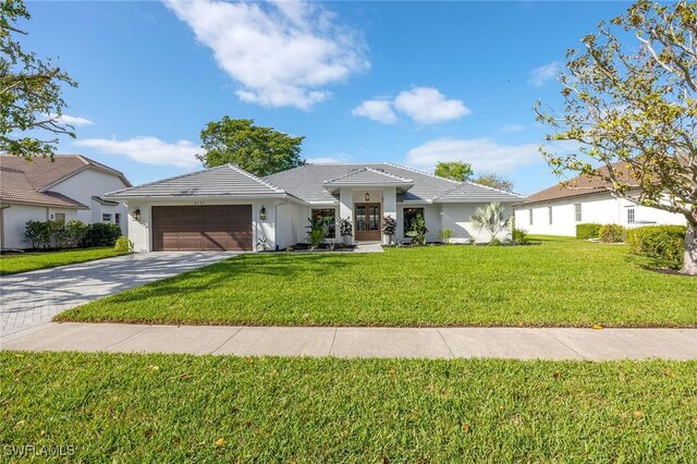 view of front of property with a garage, driveway, a tiled roof, stucco siding, and a front yard