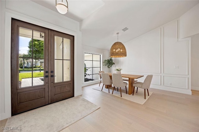 interior space with french doors, visible vents, a decorative wall, and light wood-style flooring