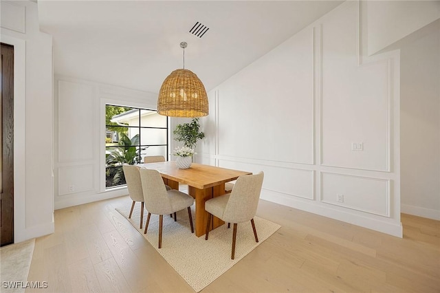 dining room featuring light wood-style floors, visible vents, and a decorative wall