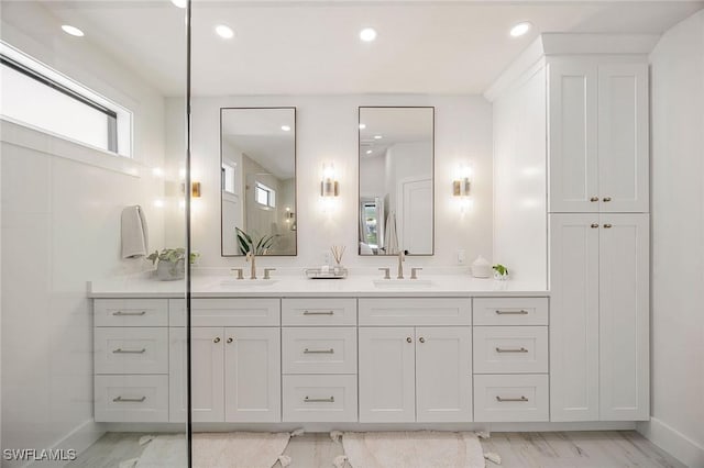 bathroom with double vanity, baseboards, a sink, and recessed lighting