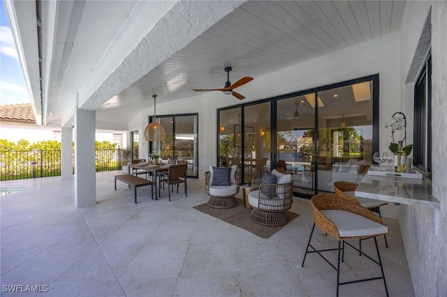 view of patio with ceiling fan, fence, and outdoor dining space